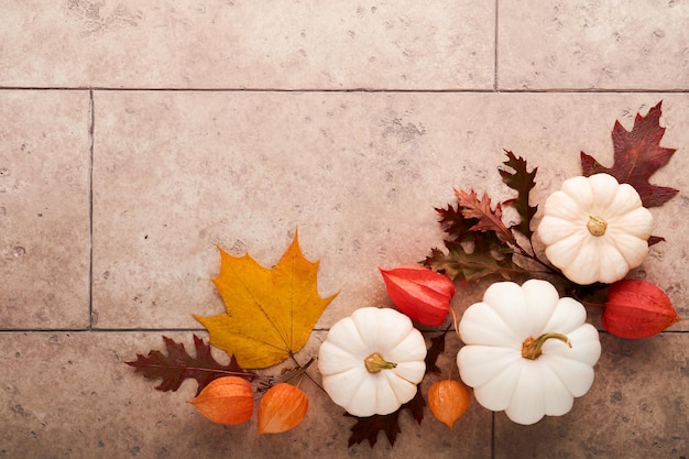 Halloween festive autumn background Autumn decor from pumpkins berries maple leaves and chestnuts on old rustic stone tiles backgrounds Concept of Thanksgiving day Halloween Top view copy space