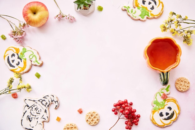Halloween festive background pumpkin cup and cookies in shape of cute pumpkins and ghost Atmospheric