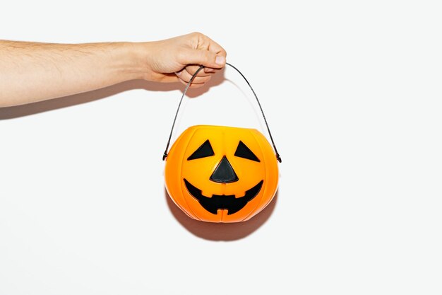 Halloween flat lay with a pumpkin basket holding by a woman on the white background.