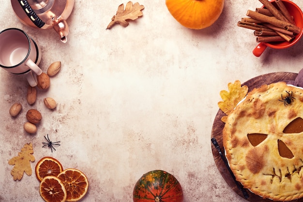 Halloween food. homemade pumpkin pie or tart with a scary face\
for halloween on a wooden table. copy space. halloween food\
concept.