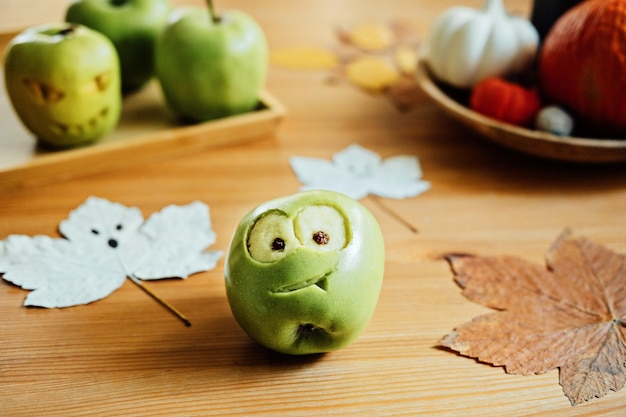 Halloween fruitideeën halloween groene appel met griezelig gesneden gezicht op houten tafel thuis gezond