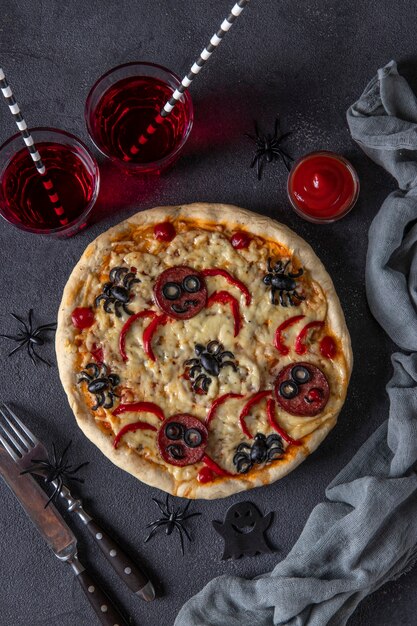 Halloween funny pizza with spiders, Creative idea for Halloween pizza on dark gray background with drinks and decorations