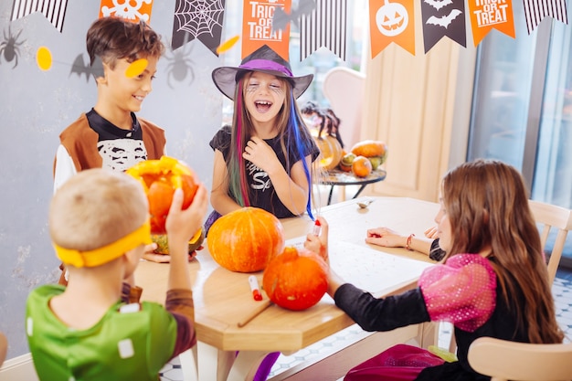 Giochi di halloween. quattro bambini di bell'aspetto emotivo che ridono che indossano costumi che giocano a divertenti giochi di halloween