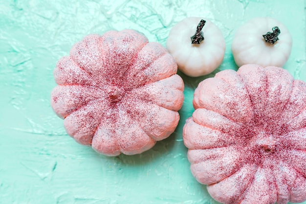 Halloween glitter pink and white pumpkins on mint background