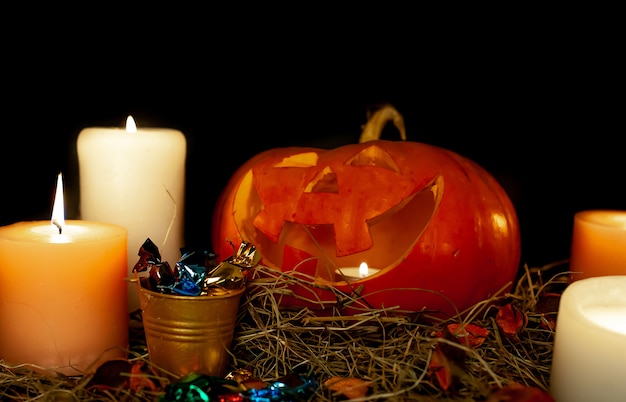 Halloween glowing pumpkins and candles on a table with a straw