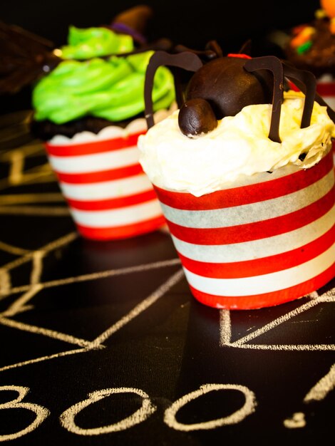 Halloween gourmet cupcakes with holiday decor black background.