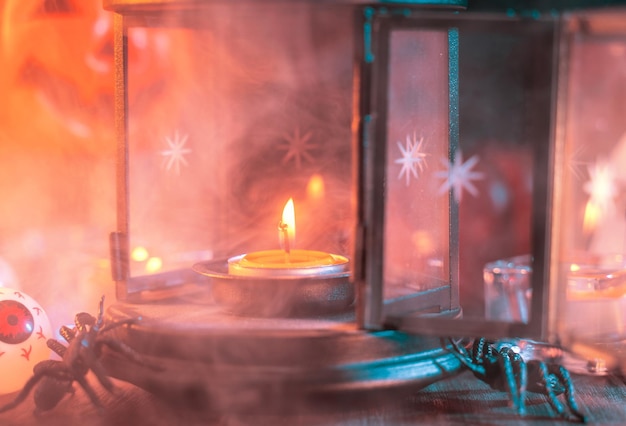 Halloween holiday concept design of pumpkin candle spooky decorations with green tone smoke around on a dark wooden table close up shot