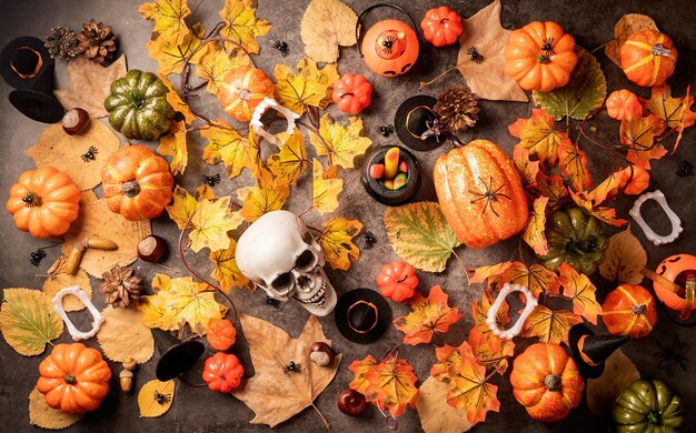 Halloween holiday decorations with pumpkins and candies top view on black backgound