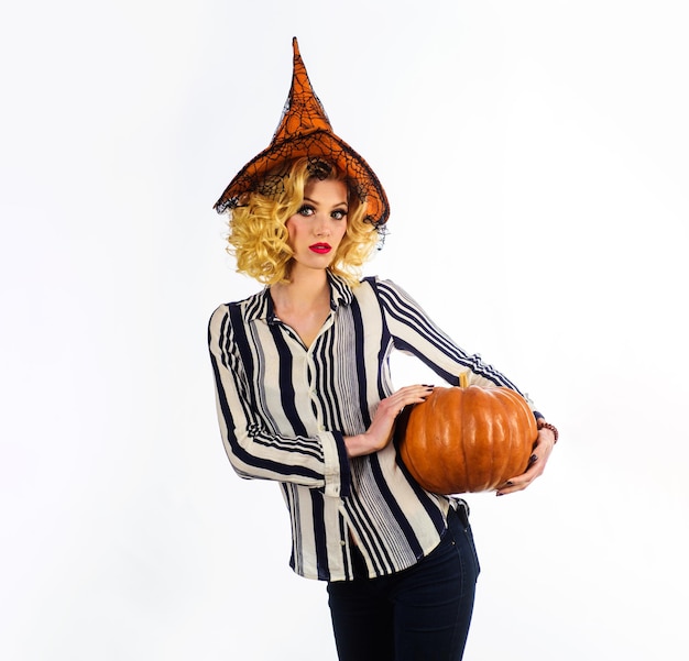 Photo halloween holiday serious girl in witch hat with pumpkin traditional food sexy woman witch in