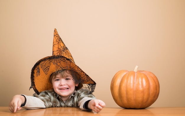 Concetto di vacanze di halloween ragazzino di halloween felice con il cappello della strega con il bambino divertente della zucca dentro