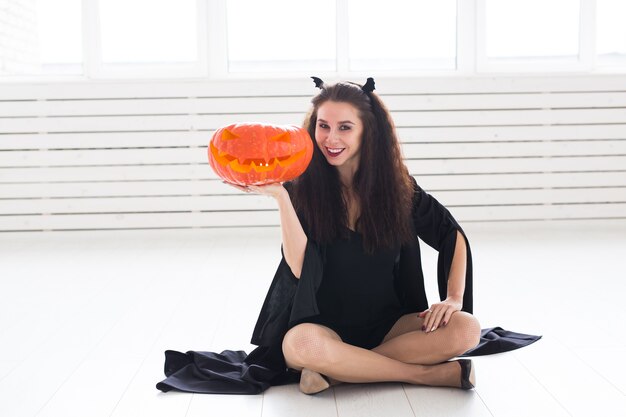 Photo halloween and holidays concept - witch woman with jack o'lantern pumpkin.