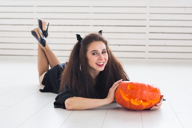 Halloween and holidays concept - Witch woman with Jack O'Lantern pumpkin.