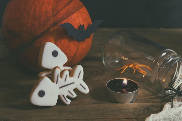 Foto halloween huisdecoratie met kaarsen spinnen pompoenkoekjes en pot voor traktatie en zwarte bessen donkere achtergrond ondiepe scherptediepte afgezwakt