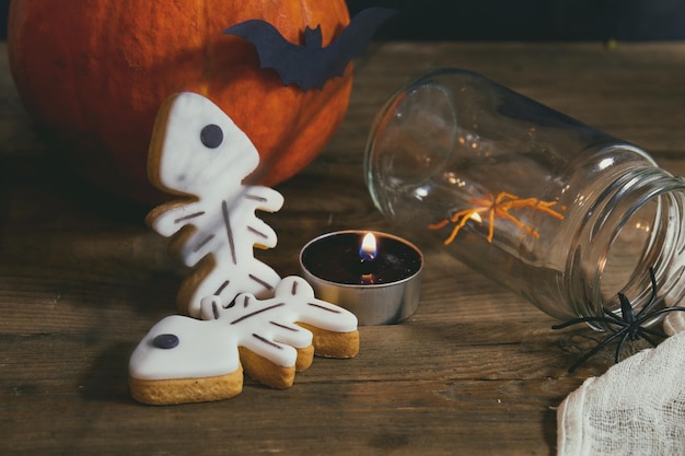 Halloween huisdecoratie met kaarsen spinnen pompoenkoekjes en pot voor traktatie en zwarte bessen Donkere achtergrond Ondiepe scherptediepte Afgezwakt