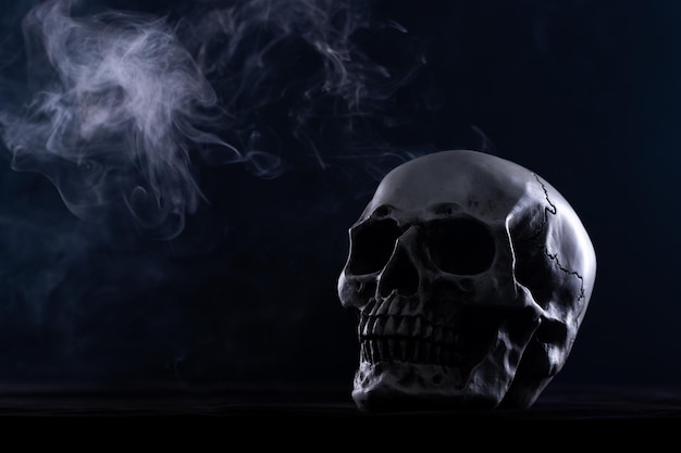 Cranio umano di halloween su un vecchio tavolo di legno su sfondo nero forma dell'osso del cranio per la testa della morte al festival di halloween che mostra paura dei denti malvagi e horror con spazio per la copia del fumo di nebbia