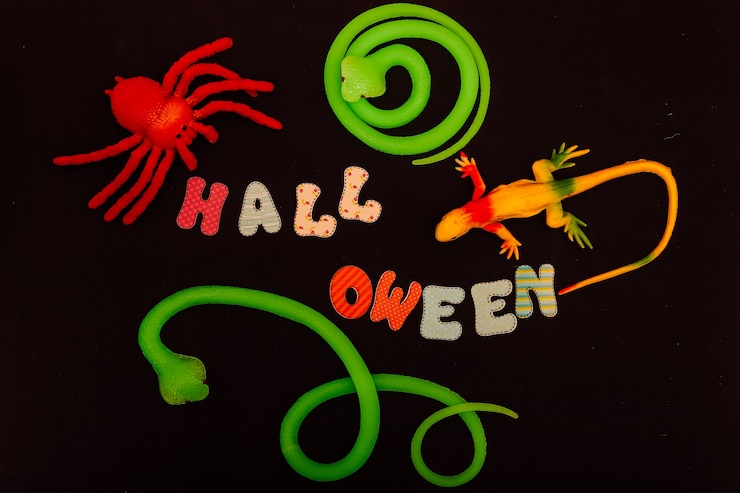 फोटो halloween inscription around a snake lizard and spider on a black table
