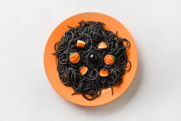 Halloween Italian black pasta decorated funny spiders in orange plate on white