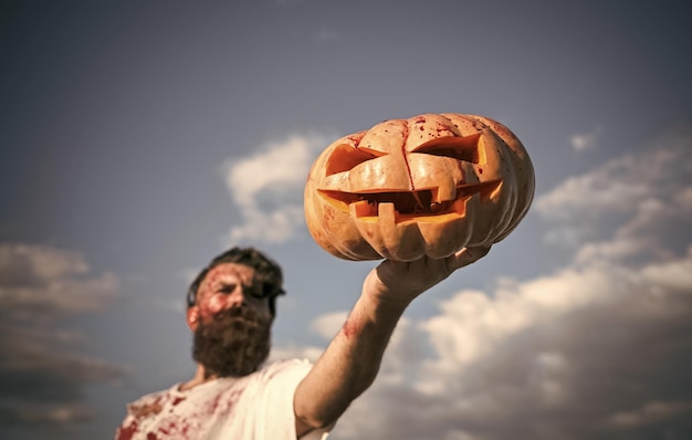 Halloween jack o lantern with red blood in zombie hand