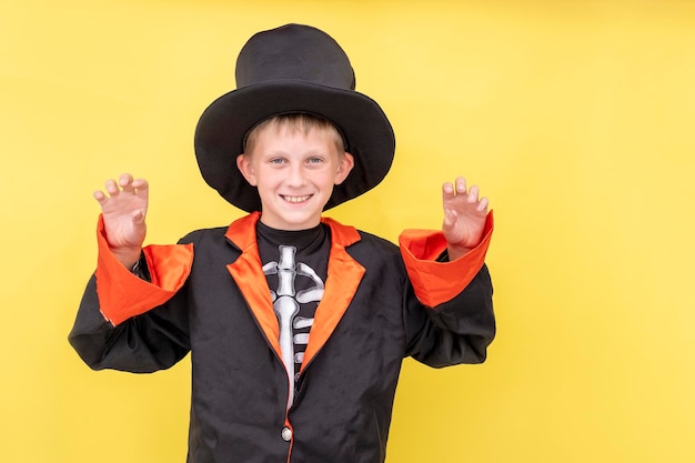 Bambini di halloween un ragazzo con un costume da scheletro tiene una lanterna jack o uno sfondo giallo spazio di copia un bambino con un cappello da cappotto nero tiene una zucca di halloween posto per il testo