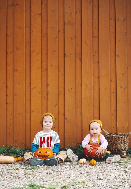 Halloween kinderfeestje Schattige kinderen met pompoenen op houten schuur achtergrond met kopie ruimte