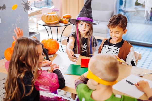 幼稚園でのハロウィーン。幼稚園でハロウィンを祝いながら楽しんでいる4人のかっこいいかわいい子供たち