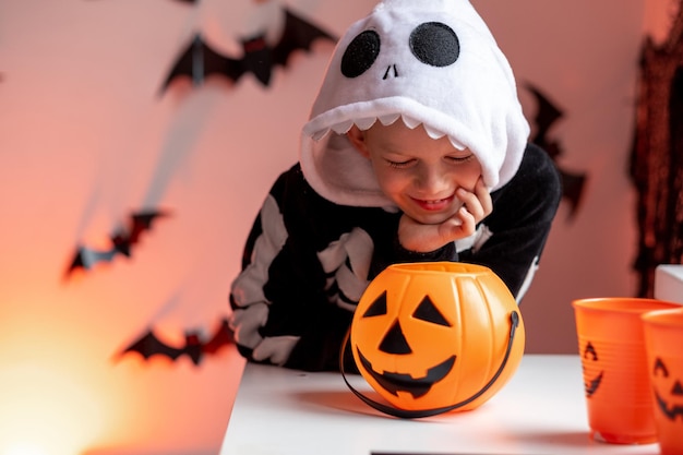 Halloween-kinderjongen met pompoenemmers in skeletkostuum thuis snoep eten Klaar voor trick or treat-vakantie
