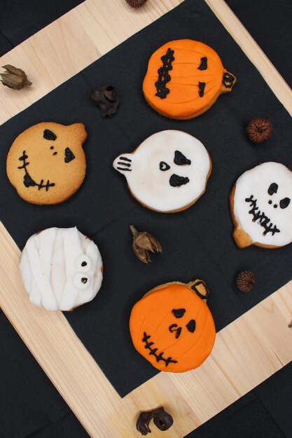 Foto halloween koekjes vorm van geesten en pompoenen witte bruine en oranje zwarte servet op houten tafel