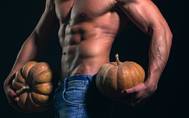 Halloween man party poster or greeting card shirtless athletic man hold pumpkin turned back on black...