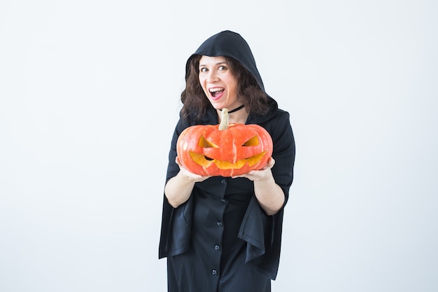 Halloween and masquerade concept - Beautiful young woman posing with Pumpkin Jack-o'-lantern