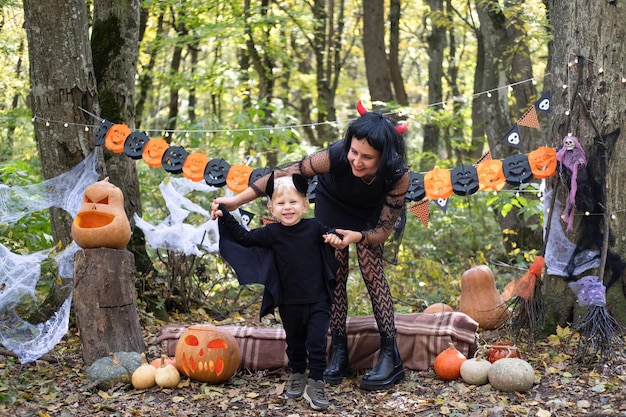 Foto la madre di halloween con il figlio piccolo in costumi di halloween che si divertono all'aperto