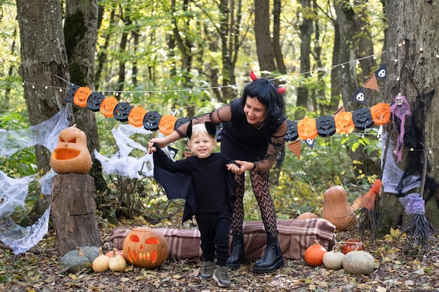 Foto halloween. madre con figlio piccolo in costumi di halloween divertendosi all'aperto