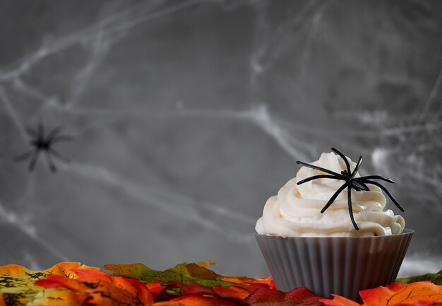 Photo halloween muffin or cupcake with white cream and spider decoration. tasty and scary food on halloween party.