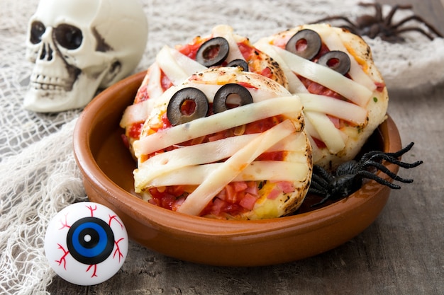 Halloween mummies mini pizzas on wooden table