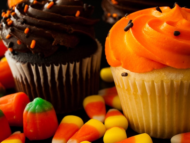 Halloween oranje en zwarte cupcakes met candy corn snoepjes op zwarte achtergrond.