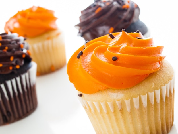 Halloween oranje en zwarte cupcakes op witte achtergrond.
