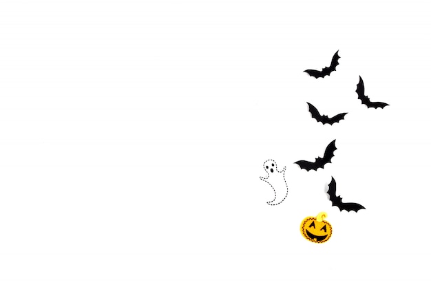 ハロウィーンのペーパーアート。白地に黒い紙コウモリ、カボチャ、幽霊を飛んでいます。