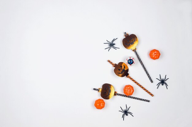 Composizione nella festa di halloween su sfondo di carta in nero, arancione e bianco. piatto, decorazioni per feste di halloween: cannucce, zucche, pipistrelli e ragni. mock-up, biglietto di auguri, disposizione piatta, vista dall'alto.