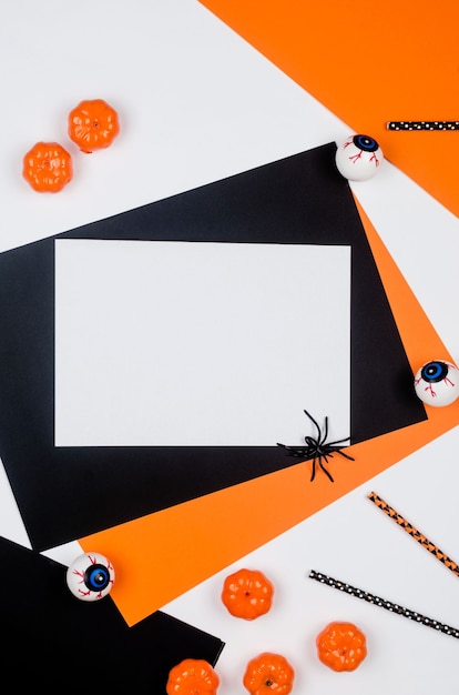 Foto composizione nella festa di halloween su sfondo di carta in nero, arancione e bianco. piatto, decorazioni per feste di halloween: cannucce, zucche, pipistrelli e ragni. mock-up, biglietto di auguri, disposizione piatta, vista dall'alto.