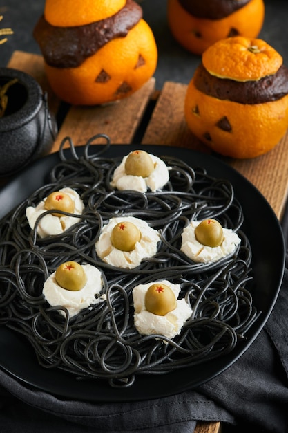 Halloween party jackolantern chocolate orange cakes against the background of the old forest branches and leaves Halloween food concept Sweets for Halloween celebration