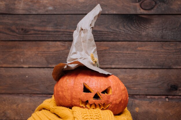 Halloween-pompoen met heksenhoed op gele sweater.