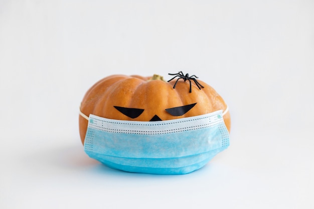 Halloween-pompoen met medisch masker en spin op witte achtergrond Pumpkin Jack met gezichtsmasker