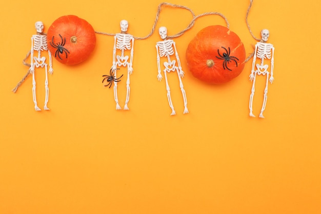 Halloween-pompoen met skeletten en zwarte spinnen op oranje achtergrond