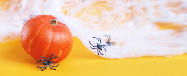 Halloween-pompoen met spinnenweb en zwarte spinnen op oranje achtergrond