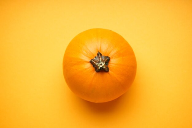 Halloween-pompoen op een gele achtergrond, plat gelegd.