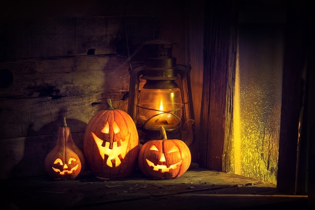 Halloween-pompoenen en lantaarn in een oud huis bij het raam waar het maanlicht schijnt.