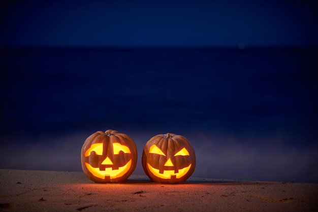 Halloween-pompoenen jack p lantaarn op het zeestrand 's nachts in het heldere maanlicht