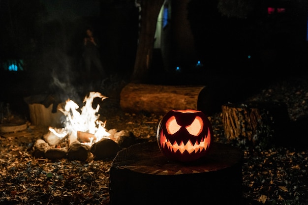 Halloween-pompoengezicht met kaars aangestoken en vuurkamp op de achtergrond Spookachtig gezicht en vijvervuur