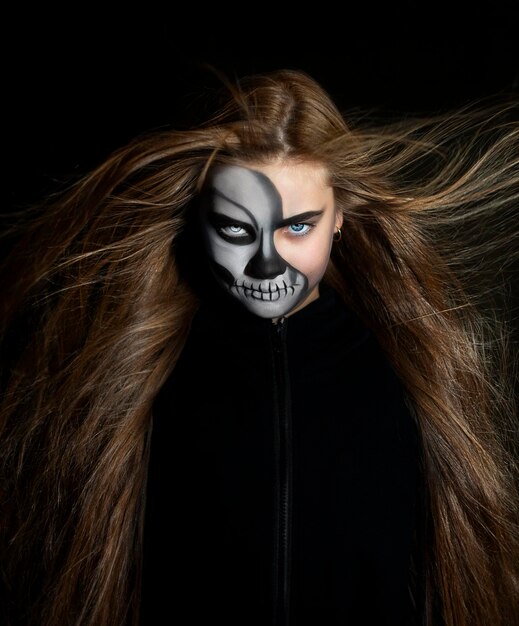 Halloween portrait of a girl with black skull makeup on dark background