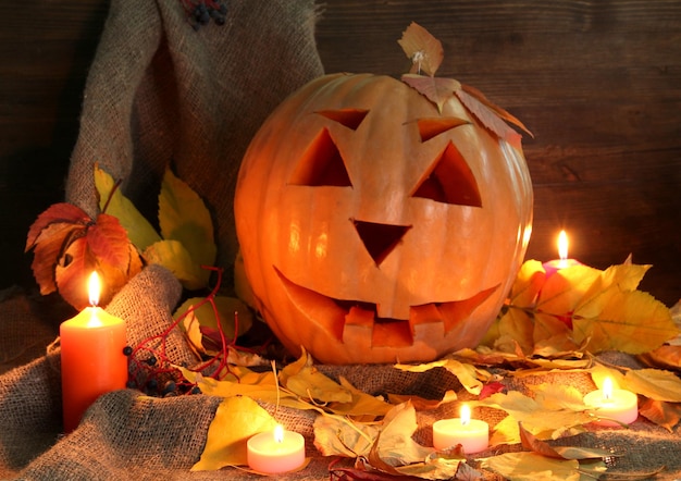 Halloween pumpkin and autumn leaves on wooden background