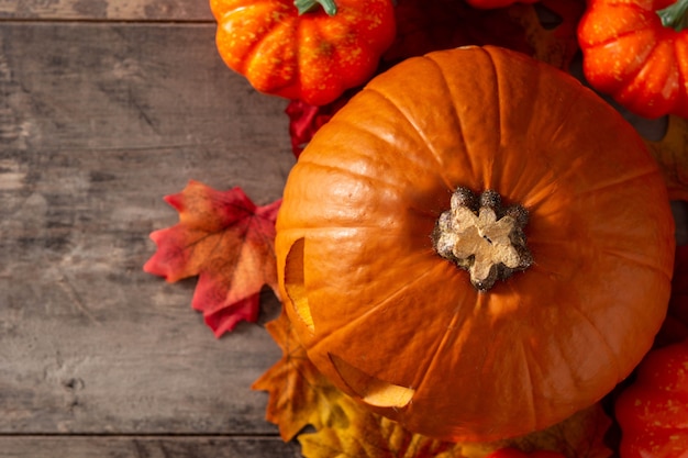 Halloween pumpkin and autumn leaves on wooden table